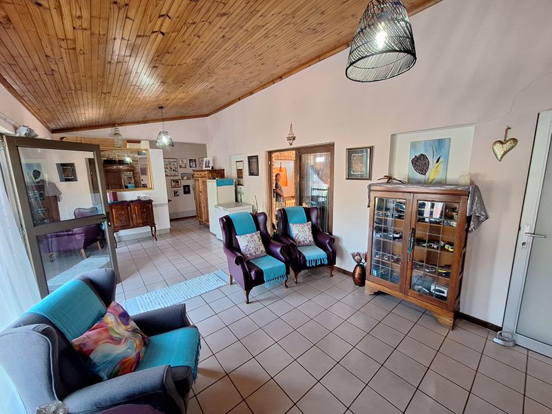 Spacious living area featuring a vaulted timber-clad ceiling, ceramic tiled flooring, and a recessed wall niche, offering a versatile layout for relaxation.