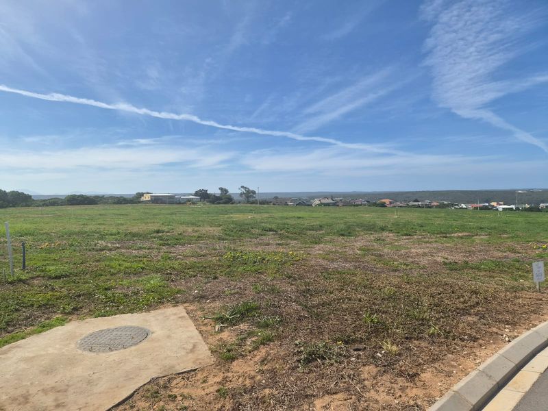 A vacant residential plot featuring level terrain, established curb infrastructure, and clear views of the surrounding neighborhood.