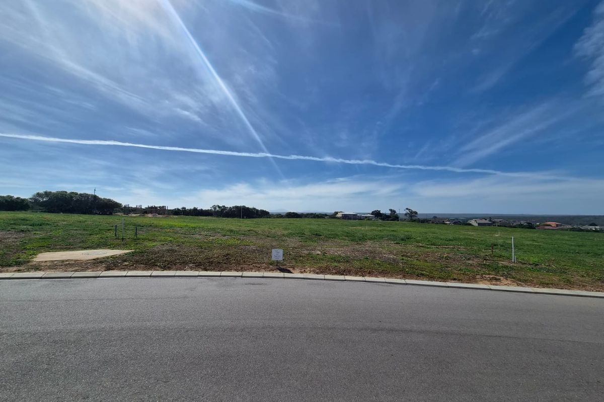 A wide-angle view of a vacant residential plot from the street, featuring level terrain and clear access to the road.