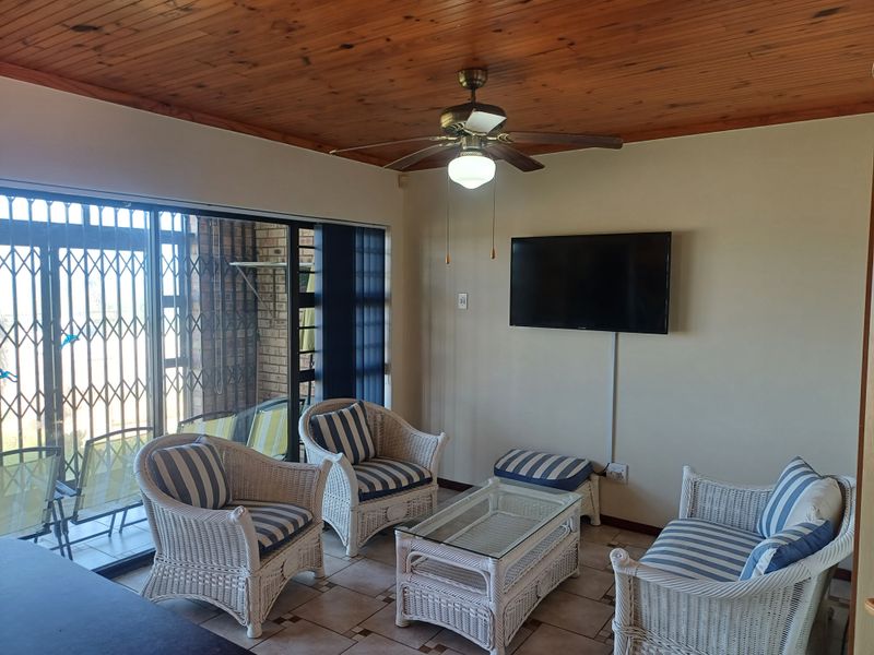 A living room featuring a timber ceiling, ceiling fan, and tiled flooring, with direct access to an outdoor area through a sliding glass door.