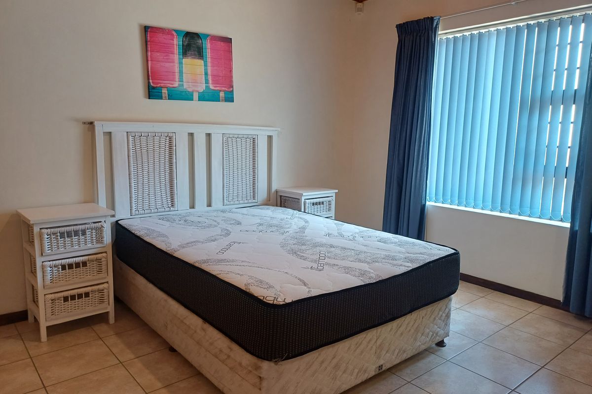 A bedroom featuring tiled flooring, vertical window blinds, and a timber ceiling finish.
