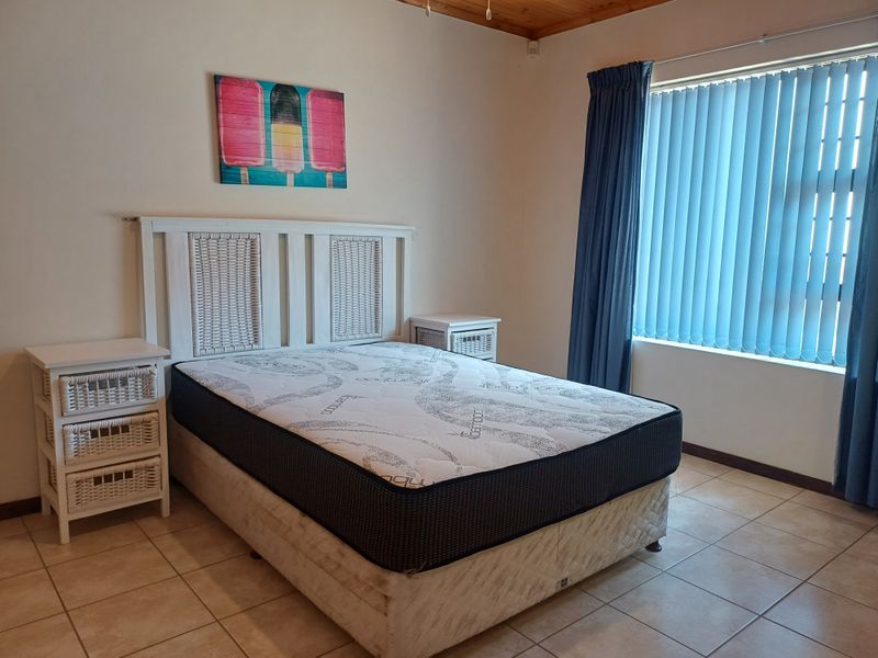 A bedroom featuring tiled flooring, vertical window blinds, and a timber ceiling finish.