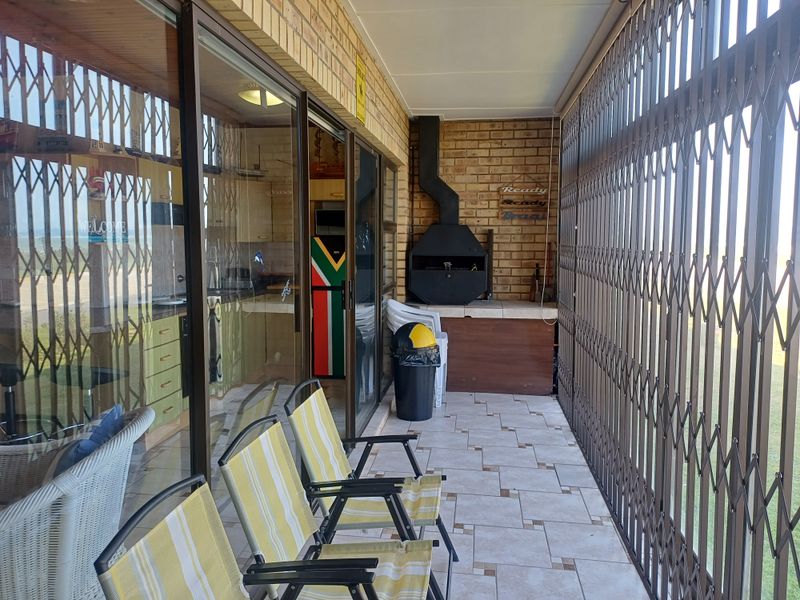 Covered patio featuring a built-in braai, tiled flooring, and secure sliding door access to the interior living space.