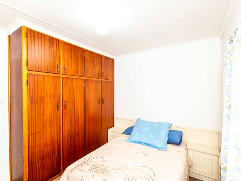 A bedroom featuring a large built-in wooden wardrobe and integrated headboard with matching bedside tables.