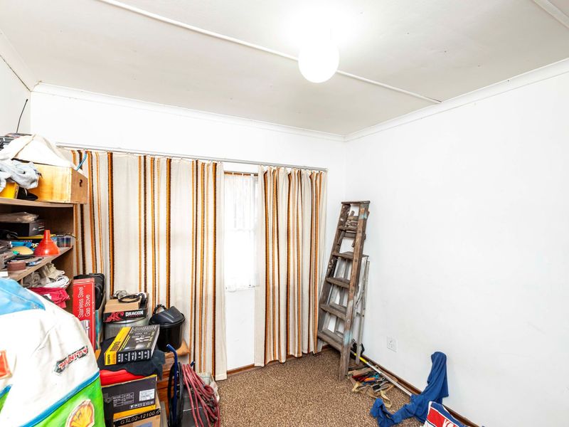 A bedroom space featuring carpeted flooring and a ceiling light fixture, currently utilized for storage.
