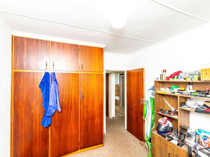 Bedroom featuring built-in wooden cupboards and carpeted flooring, providing functional storage space with potential for modernization.