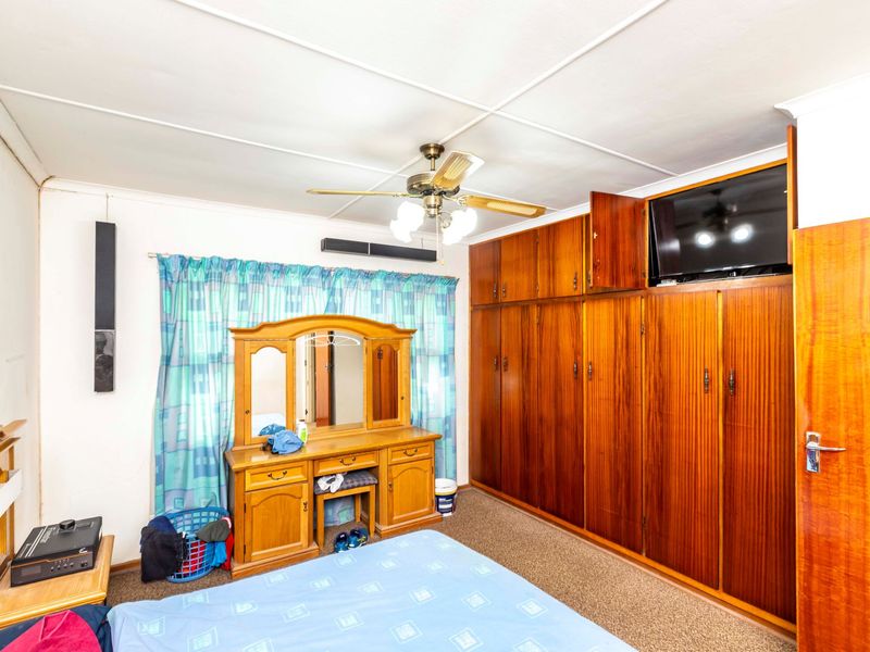 A bedroom featuring extensive built-in wooden cabinetry, a ceiling fan, and carpeted flooring, offering functional storage space.