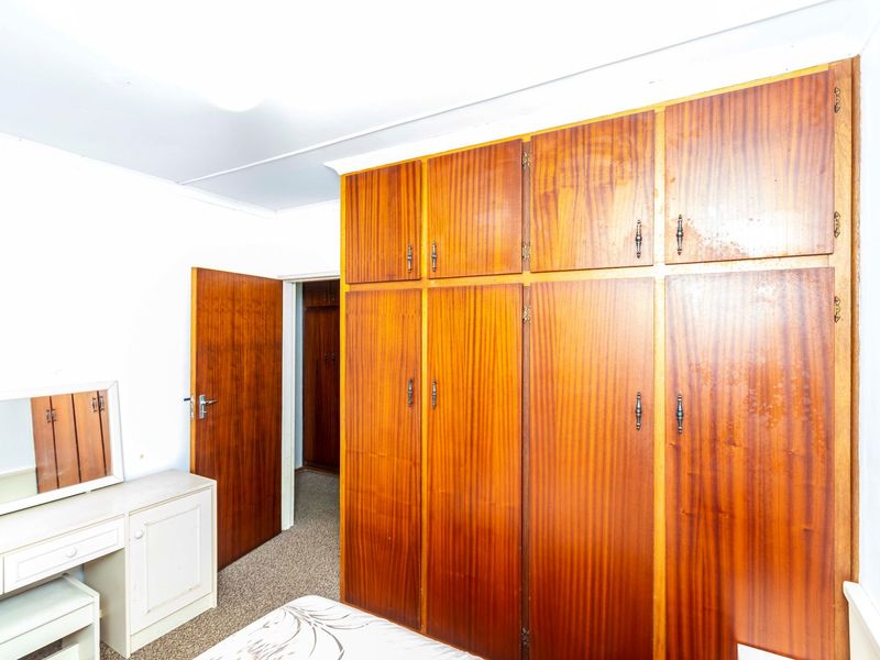 Bedroom featuring extensive built-in wooden cabinetry and carpeted flooring, offering ample storage space in a traditional layout.
