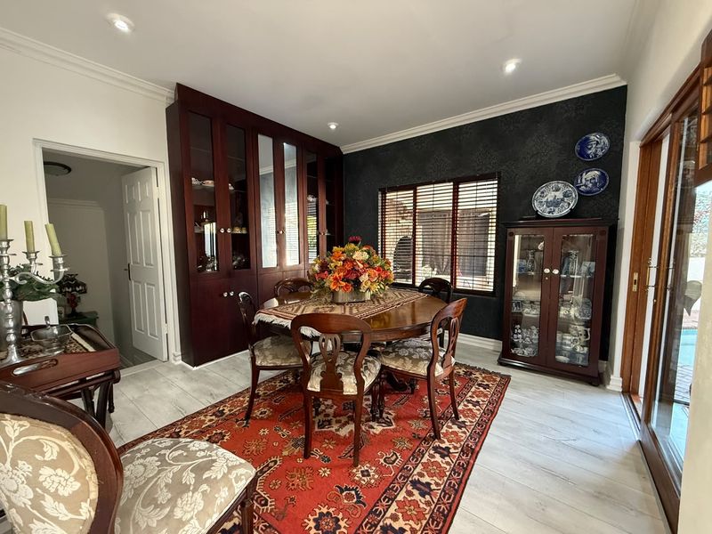 Formal dining room featuring built-in dark wood display cabinetry, tiled flooring, recessed lighting, and direct access to the outdoor area via sliding glass doors.