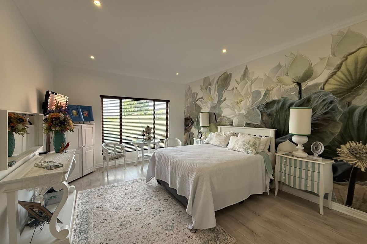 A well-maintained bedroom featuring laminate flooring, recessed downlighting, and a large feature wall mural, providing a bright and comfortable living space.