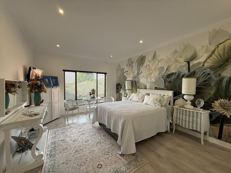 A well-maintained bedroom featuring laminate flooring, recessed downlighting, and a large feature wall mural, providing a bright and comfortable living space.