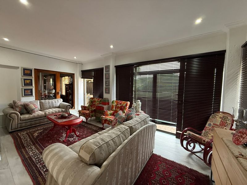 Spacious living room featuring recessed downlighting, coved cornicing, and large sliding glass doors with timber venetian blinds providing access to the outdoor area.