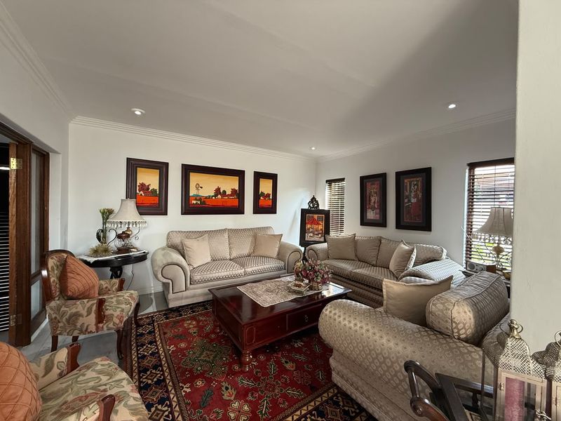 A well-maintained living room featuring crown molding, recessed downlighting, and venetian blinds, providing a comfortable and classic living space.