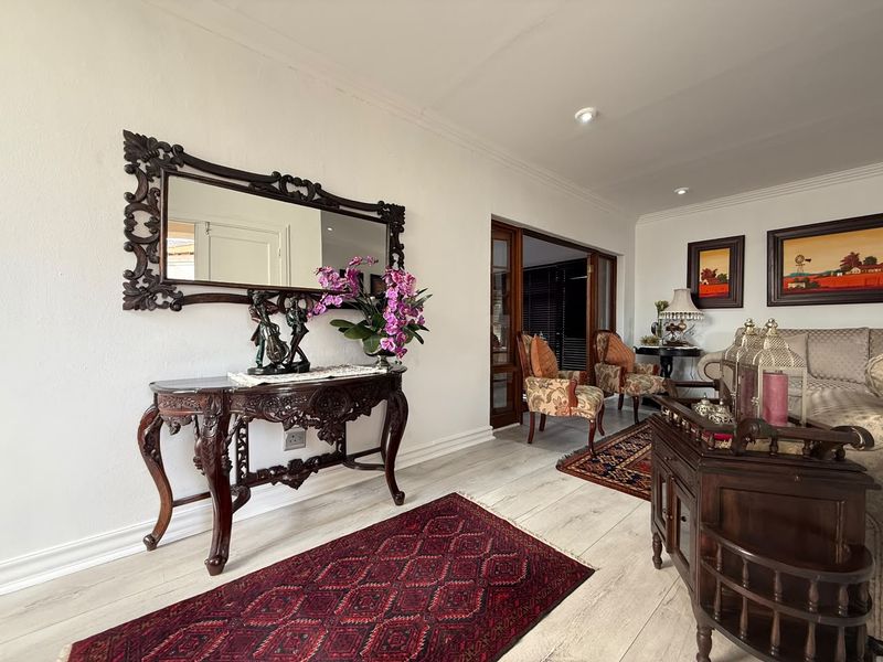 A well-maintained living area featuring light-toned timber-look flooring, recessed downlighting, and sliding glass doors leading to an adjacent space.