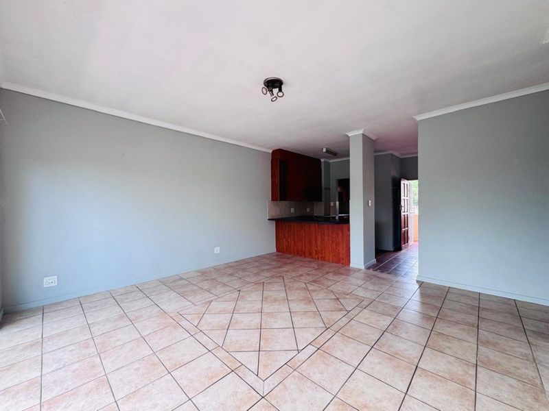Open plan living area featuring tiled flooring and a view through to the kitchen and entrance.