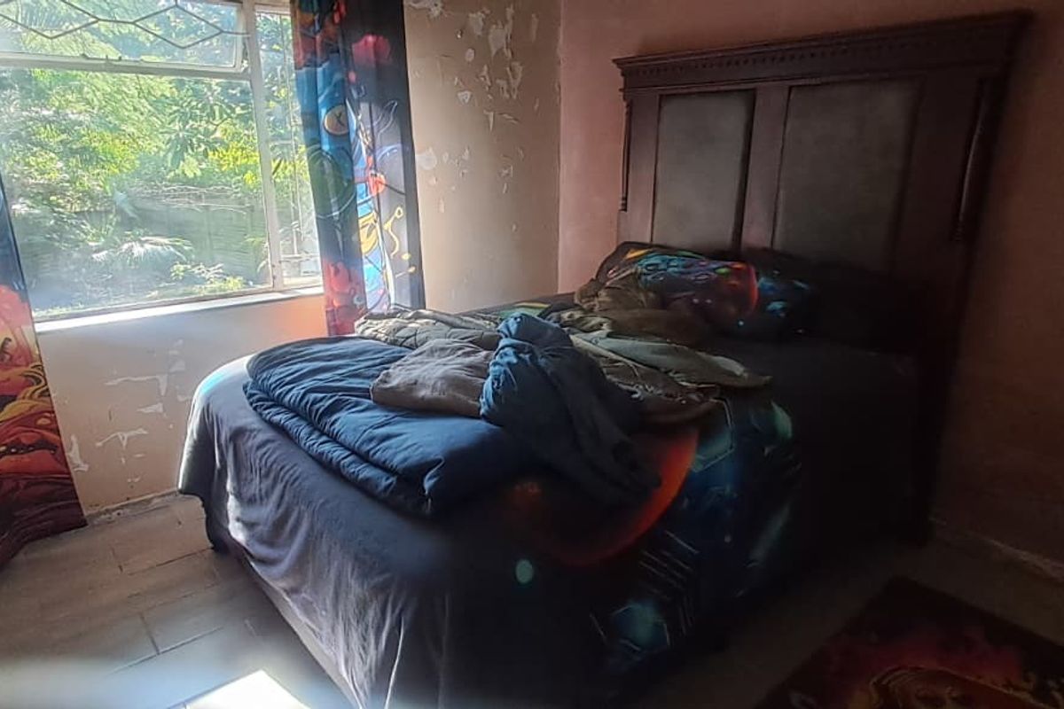 A bedroom featuring a window with natural light, requiring significant wall repairs and cosmetic updates to improve the overall condition.