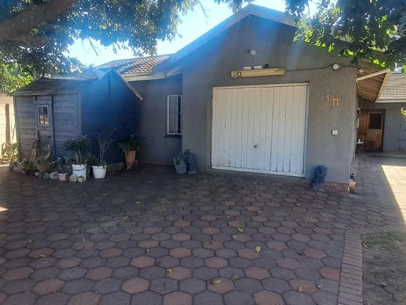 Front exterior view of the property featuring a paved driveway, single garage, and established garden surroundings.