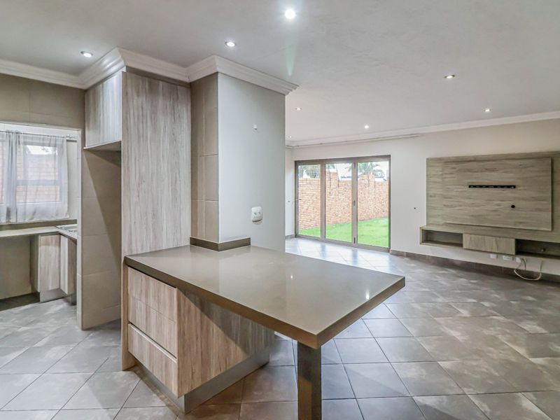 Spacious open-plan living area featuring a modern kitchen with stone countertops, breakfast nook, and seamless flow to the rear garden through sliding glass doors.