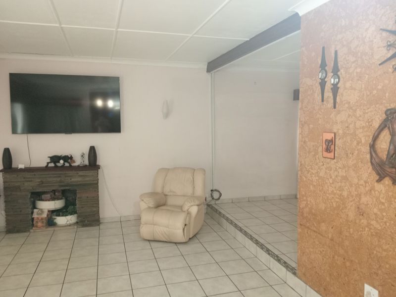 Living room featuring a stone fireplace, tiled flooring, and a raised floor section, offering a dated interior space ready for modernization.