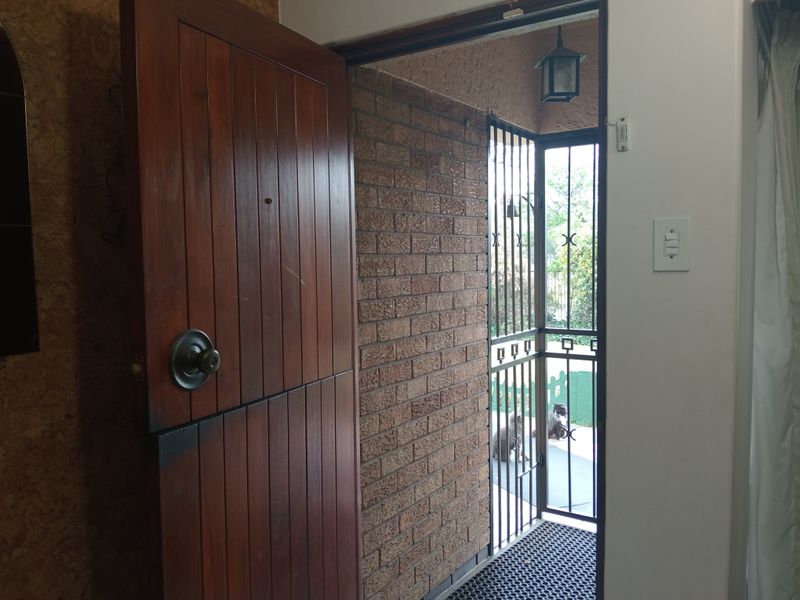 Entrance area featuring a timber stable door, security gate, and exposed brick wall finish.