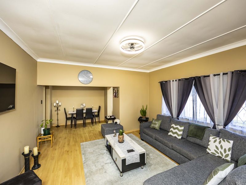 Open plan living and dining area featuring laminate flooring, coved ceilings, and a central ceiling fan, providing a functional and connected living space.