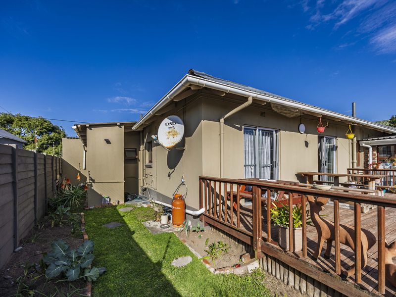 Rear exterior view featuring a timber deck, garden area, and access to the home via glass sliding doors.
