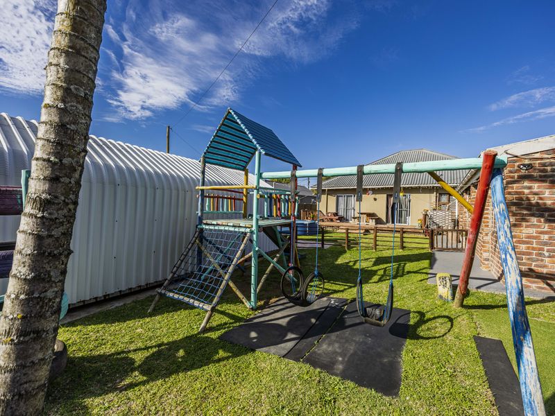 A spacious backyard garden featuring a lawn area, a corrugated metal storage shed, and a brick boundary wall.