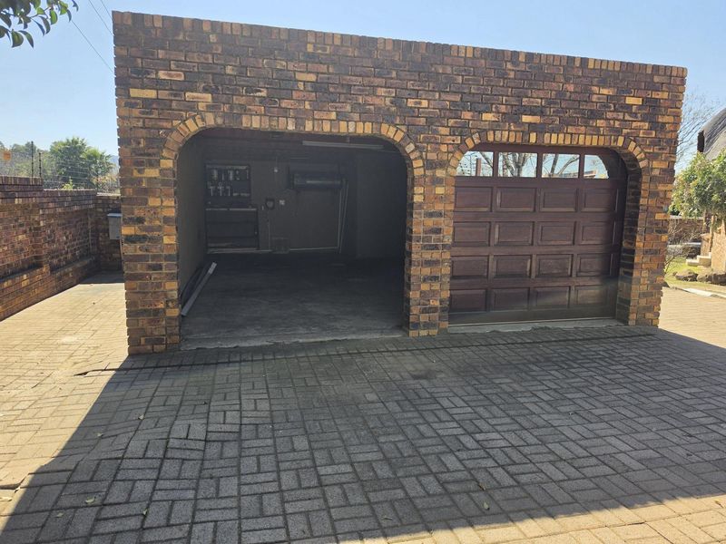 A detached face brick garage featuring a paved driveway and a sectional door, providing secure parking and storage space.