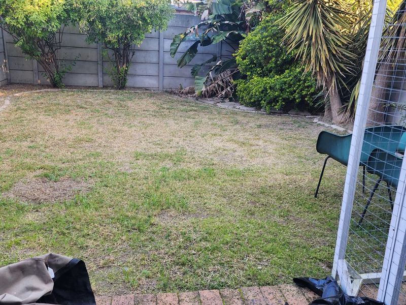 A private rear garden featuring a lawn area, established perimeter landscaping, and a precast concrete boundary wall.