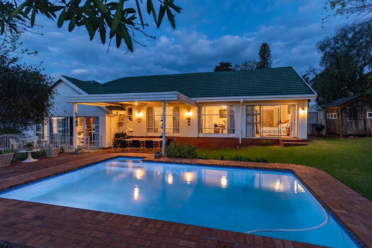 Rear view of the property featuring a swimming pool, brick-paved surround, and a covered patio area leading into the home.