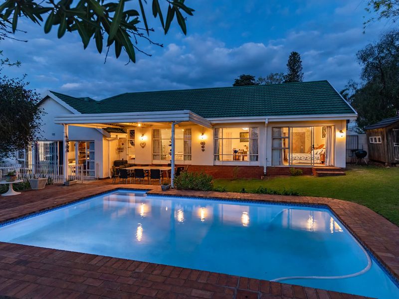 Rear view of the property featuring a swimming pool, brick-paved surround, and a covered patio area leading into the home.