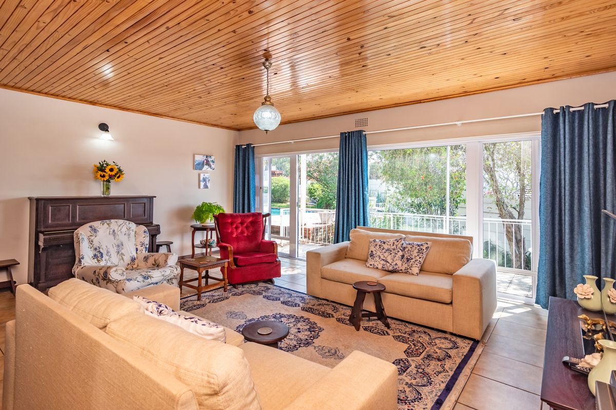 Spacious living room featuring a warm timber tongue and groove ceiling, tiled flooring, and large sliding glass doors providing access to the outdoor area.