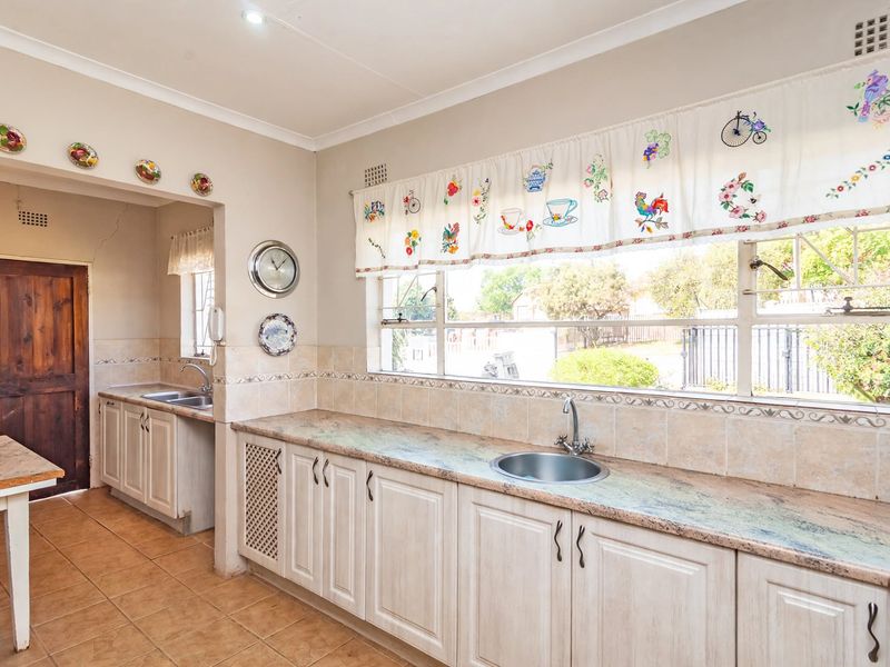 A functional kitchen featuring ample built-in cabinetry, stone countertops, dual sink areas, and tiled finishes, offering a practical layout with natural light.