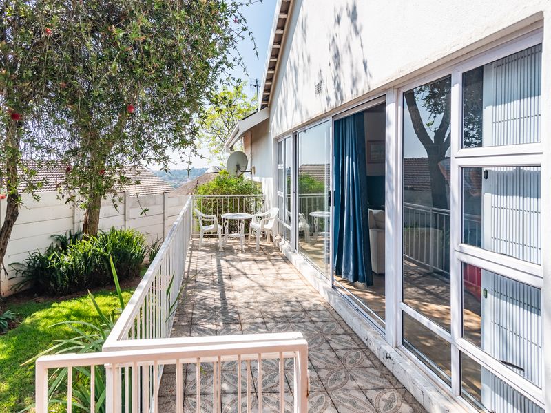 A covered patio area featuring tiled flooring, a metal balustrade, and large sliding glass doors providing access to the interior living space.