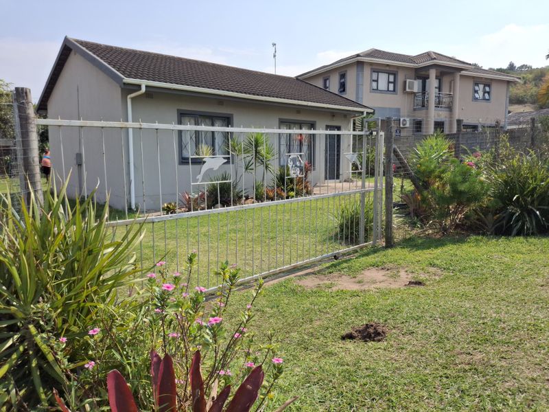 Front view of a single-story residential house featuring a metal security gate, tiled roof, and established garden area.