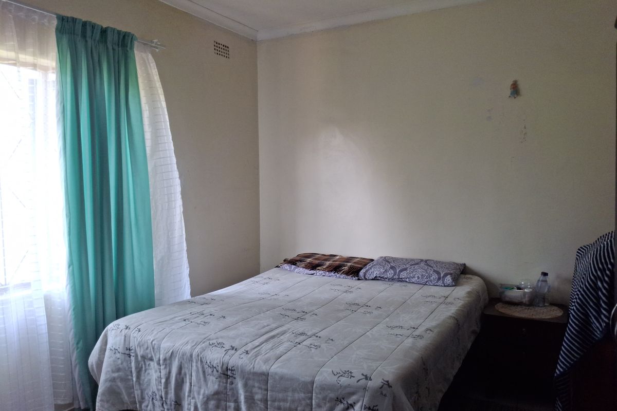A standard bedroom featuring neutral walls and a window with curtain fixtures, providing a functional space for rest.
