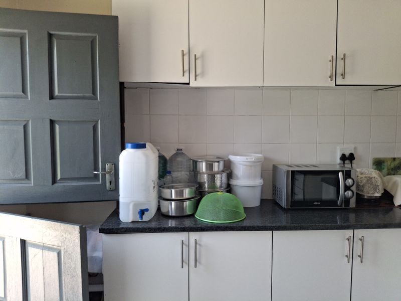 A functional kitchen area featuring white built-in cabinetry, a dark laminate countertop, and a tiled backsplash.