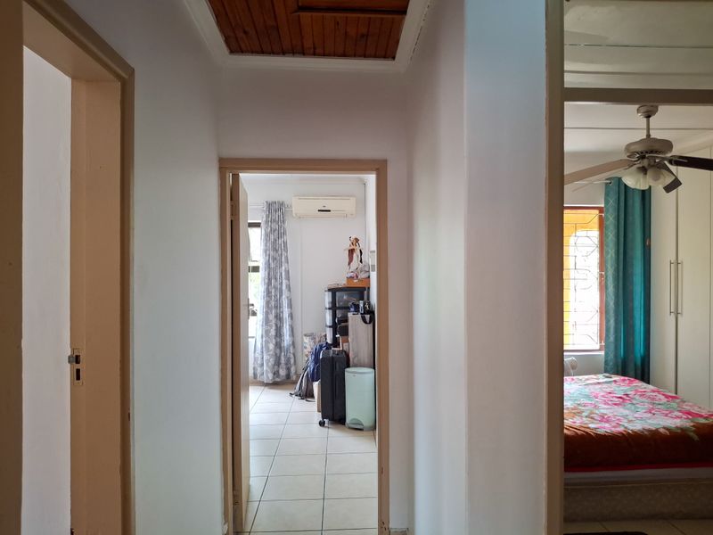 A central hallway connecting multiple rooms, featuring tiled flooring and access to a ceiling hatch, providing a functional transition space within the home.