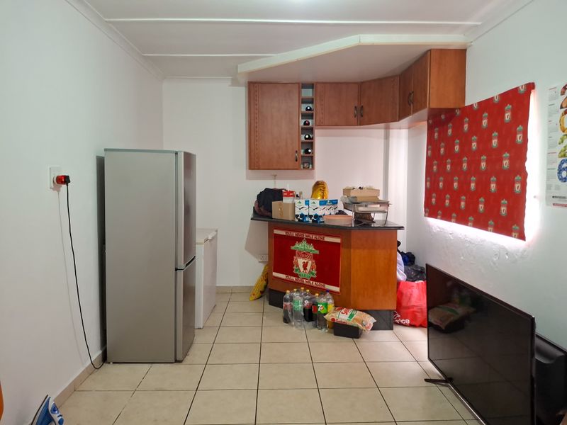 A functional kitchen area featuring built-in wooden cabinetry, a breakfast bar counter, and tiled flooring.