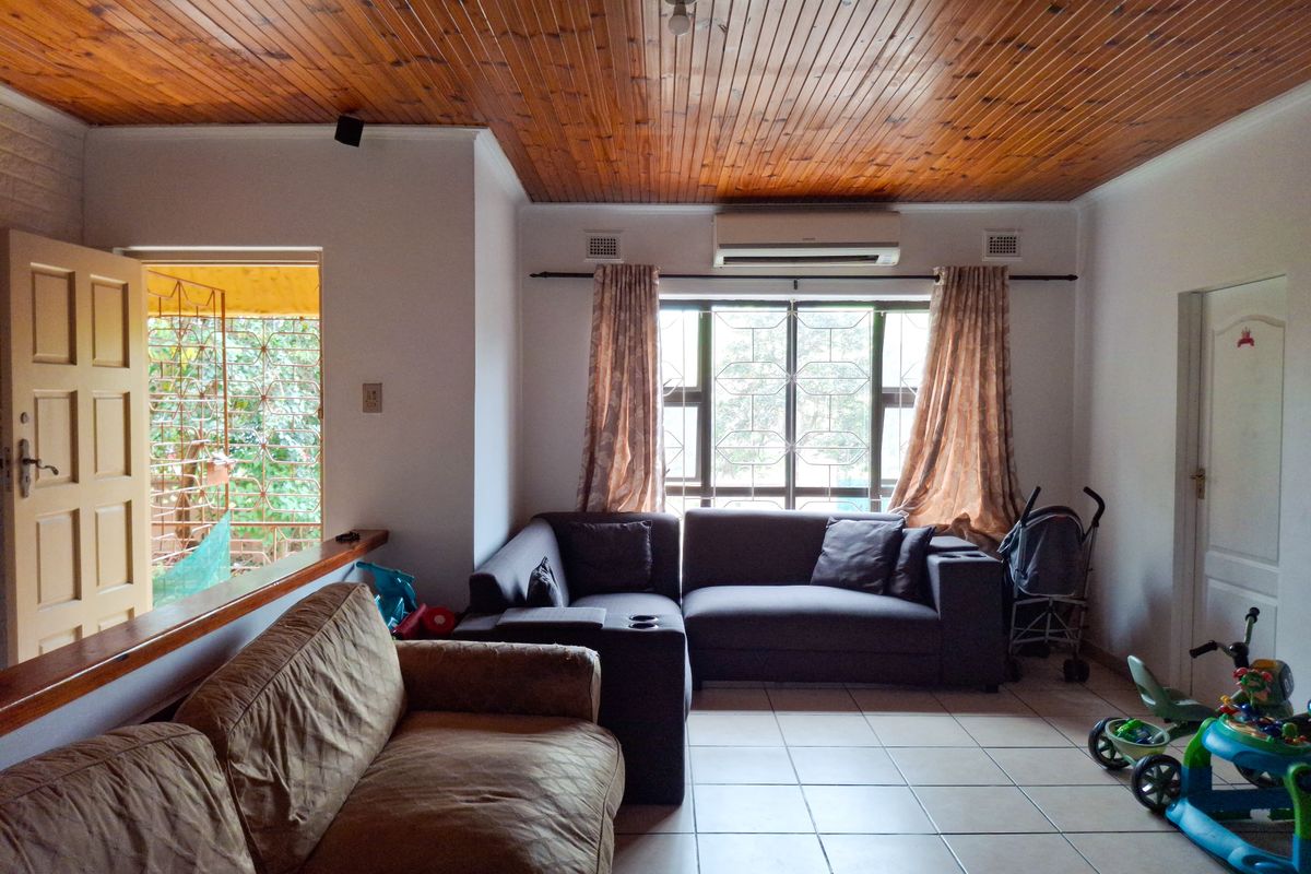 Living room featuring tiled flooring, a timber tongue and groove ceiling, and a wall-mounted split system air conditioner.