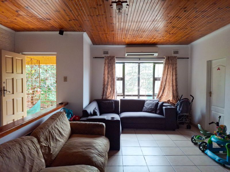 Living room featuring tiled flooring, a timber tongue and groove ceiling, and a wall-mounted split system air conditioner.
