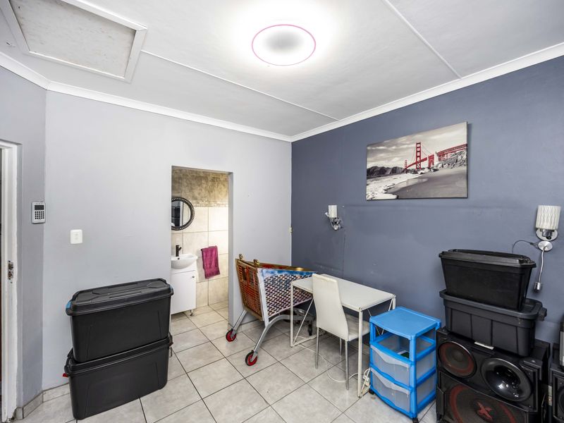 A bedroom featuring tiled flooring, coving, and a ceiling light fixture, with an adjoining en-suite bathroom visible through the doorway.