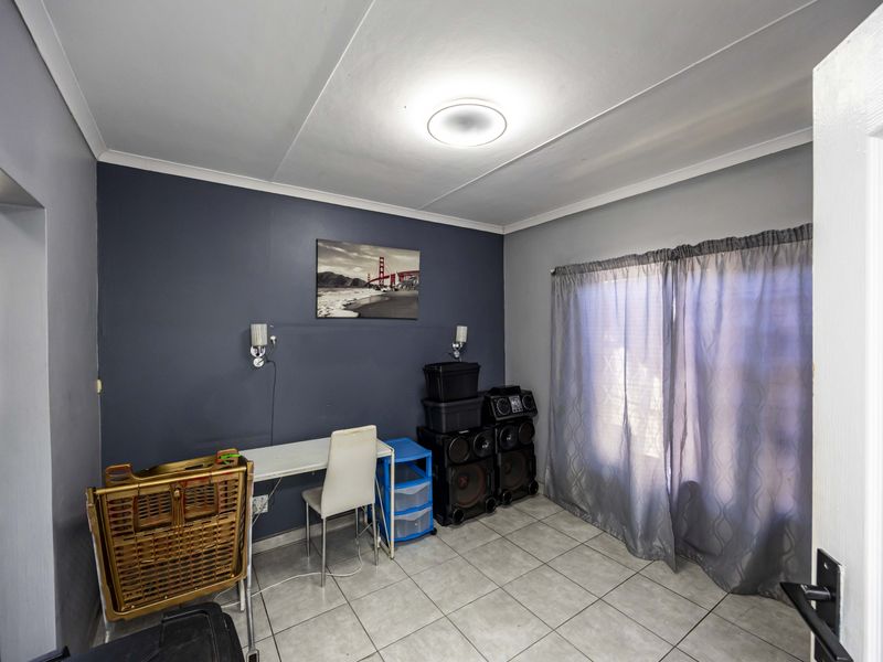 A bedroom featuring tiled flooring, neutral wall finishes, and integrated wall lighting, with direct access to an adjacent bathroom area.