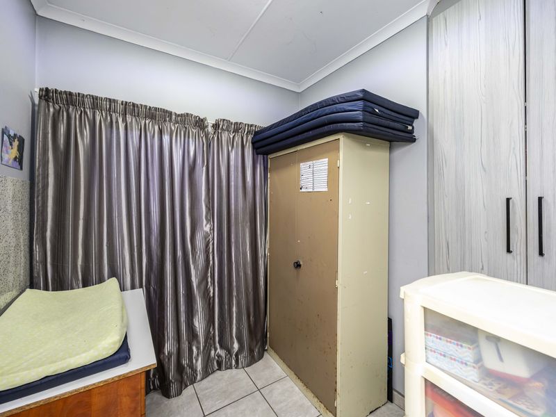 A bedroom featuring built-in cupboards, tiled flooring, and coved ceilings, offering a functional space ready for personalization.