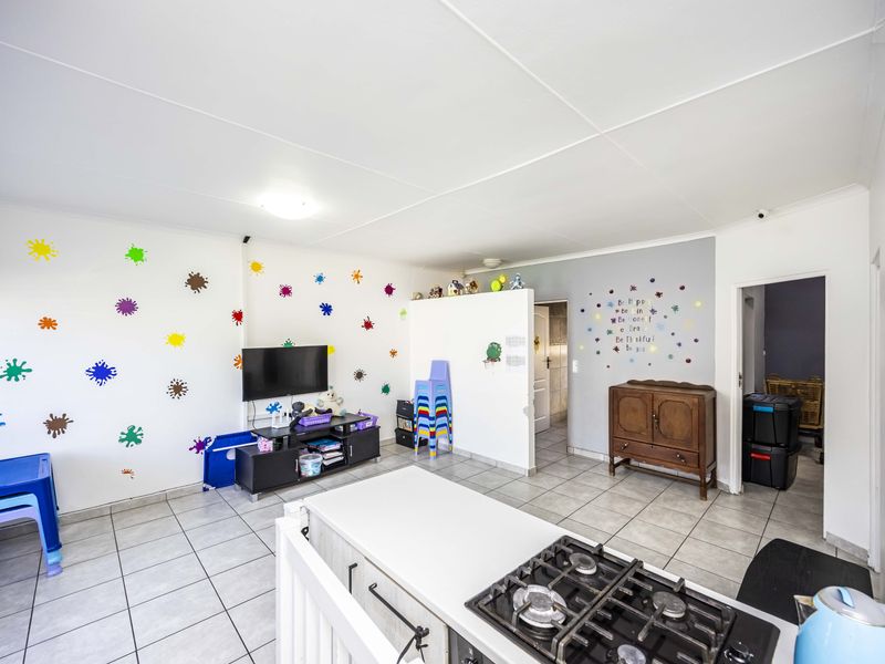 Open plan living area featuring tiled flooring and a kitchen island with a built-in gas hob, providing a functional and versatile space.
