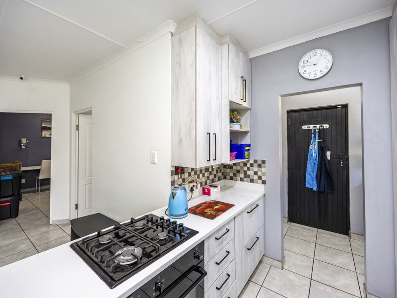 A functional kitchen featuring light wood-grain cabinetry, a built-in gas hob and oven, and a classic checkered tile backsplash.