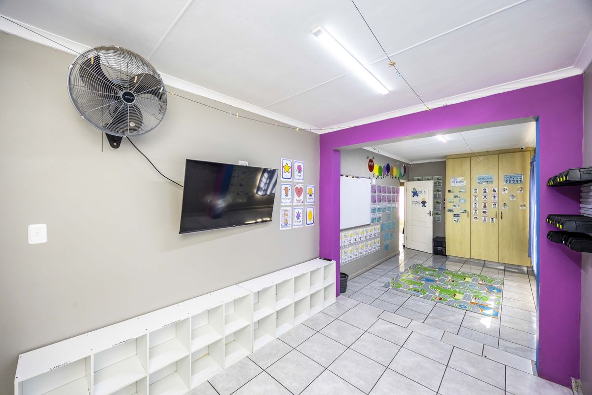A multi-purpose living area featuring tiled flooring, built-in storage shelving, and integrated cupboards, currently utilized as a learning or activity space.