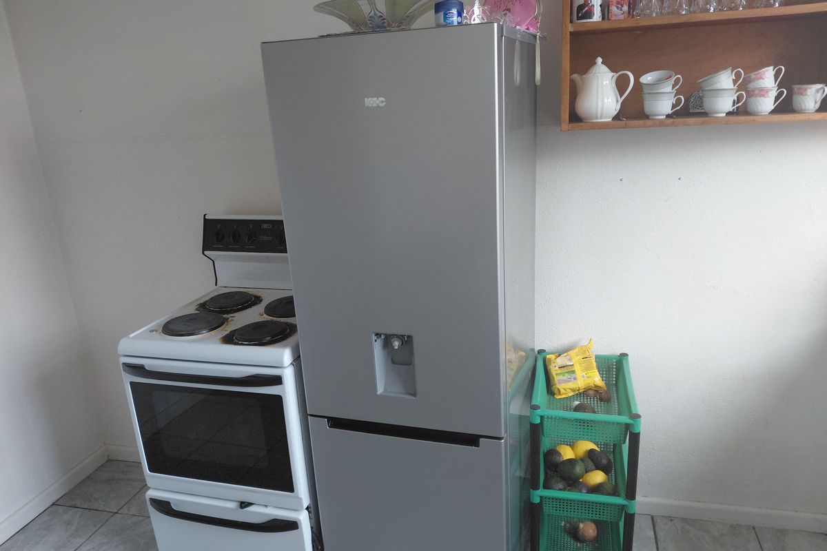 A compact kitchen area featuring a freestanding electric stove and tiled flooring, requiring cosmetic updates to improve the overall aesthetic.