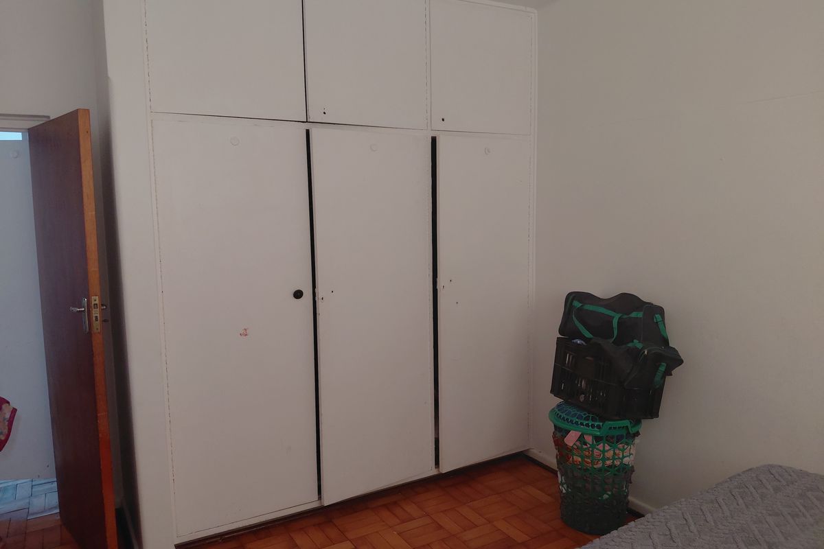A bedroom featuring classic parquet flooring and floor-to-ceiling built-in cupboards providing ample storage space.