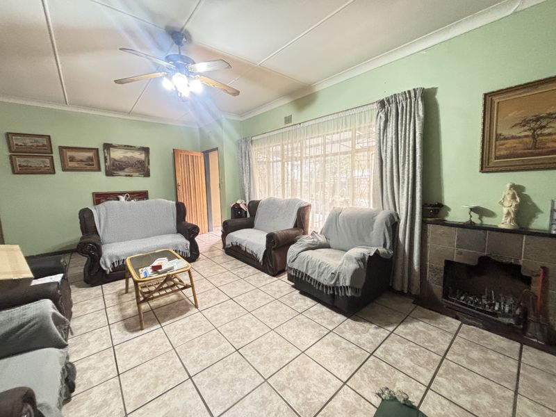 Spacious living room featuring tiled flooring, a stone fireplace, and a ceiling fan, with direct access to the outdoor area through sliding glass doors.